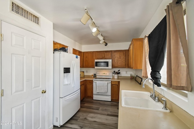 kitchen featuring white appliances, visible vents, brown cabinets, and a sink