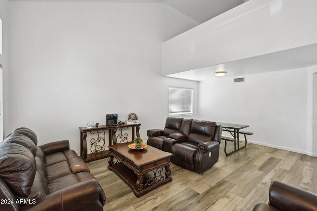 living room with light wood-type flooring and high vaulted ceiling