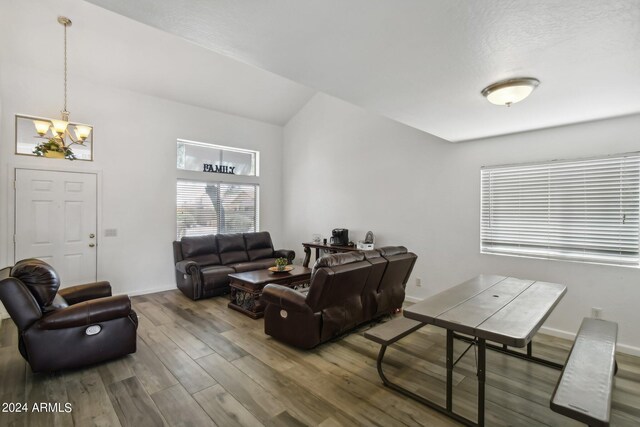 living room featuring vaulted ceiling, wood-type flooring, and a chandelier