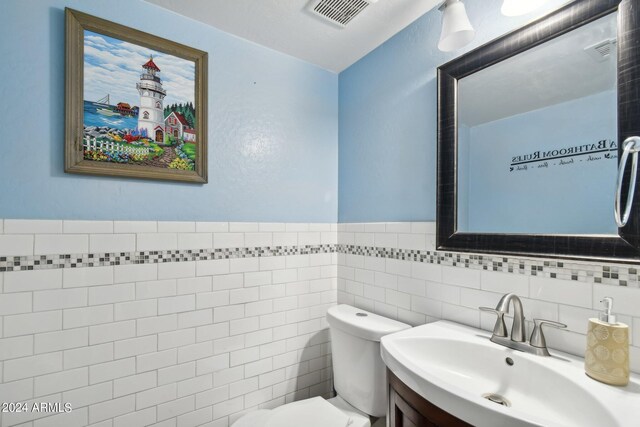 bathroom featuring tile walls, backsplash, vanity, and toilet