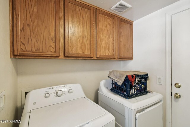 clothes washing area with washer and clothes dryer and cabinets