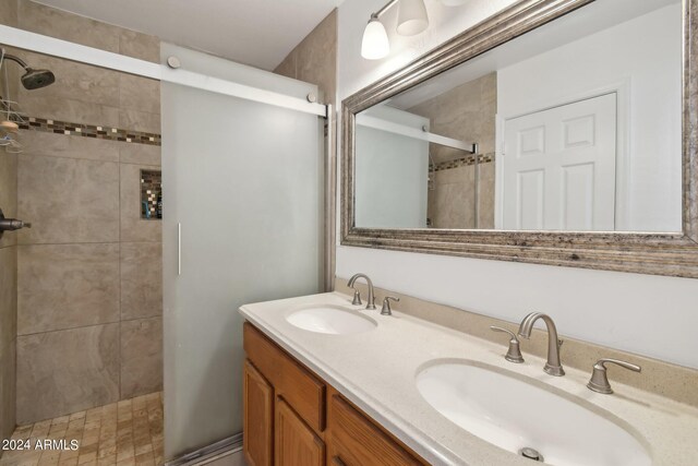 bathroom featuring tiled shower and vanity