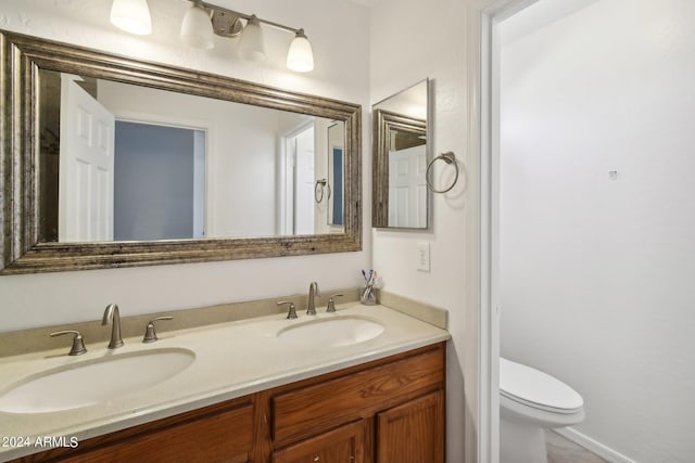 bathroom featuring double vanity, a sink, and toilet