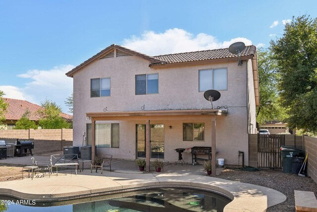 back of property featuring a fenced in pool and a patio area