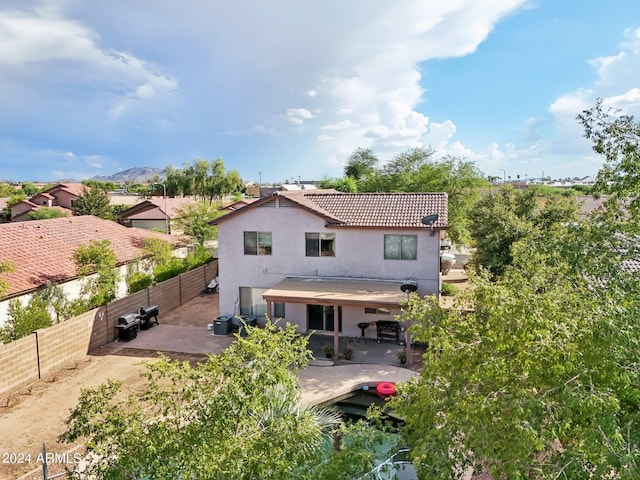 rear view of property featuring a patio, a fenced backyard, a tiled roof, and stucco siding