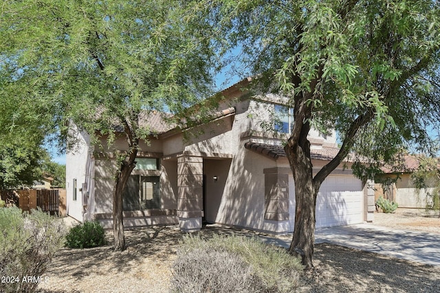 view of front of property with concrete driveway, fence, a tile roof, and stucco siding