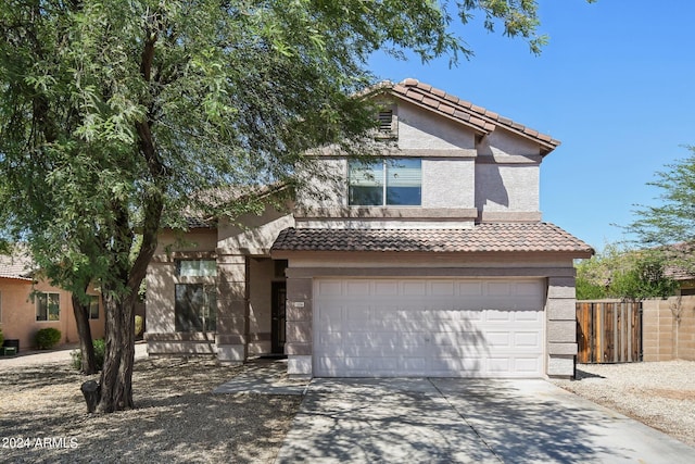 view of front of house with a tile roof, stucco siding, an attached garage, fence, and driveway