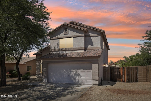 view of front of house with a garage, fence, a tiled roof, and stucco siding