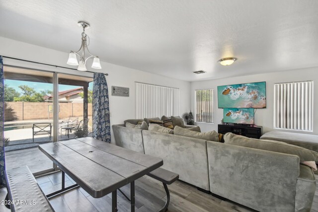 living room with a wealth of natural light, light hardwood / wood-style flooring, and a notable chandelier