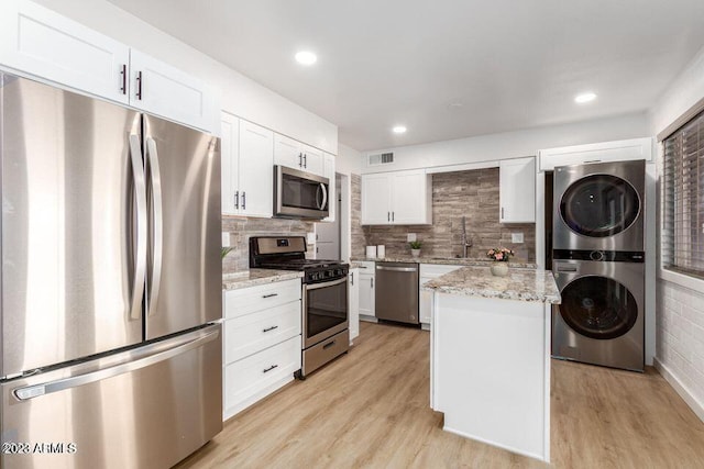 kitchen with stacked washer and clothes dryer, a kitchen island, light hardwood / wood-style flooring, and stainless steel appliances