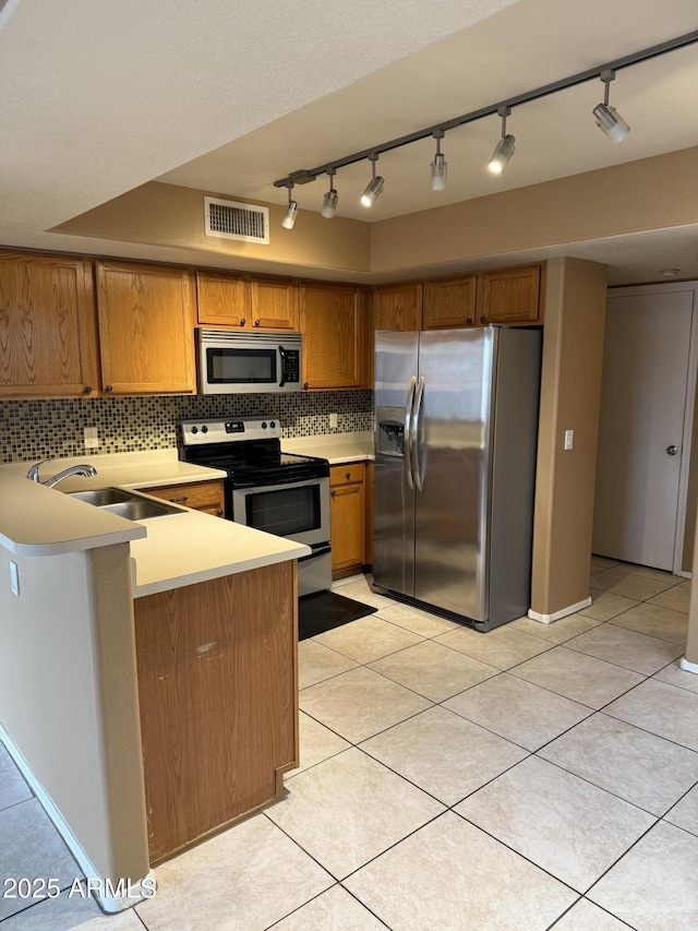 kitchen with stainless steel appliances, decorative backsplash, sink, kitchen peninsula, and light tile patterned floors