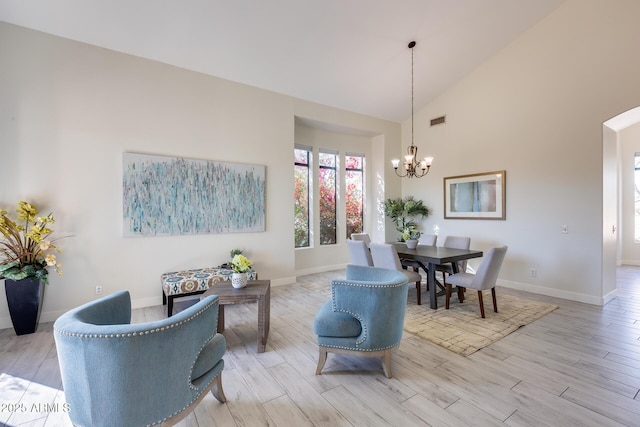 dining space featuring high vaulted ceiling, light hardwood / wood-style floors, and a chandelier