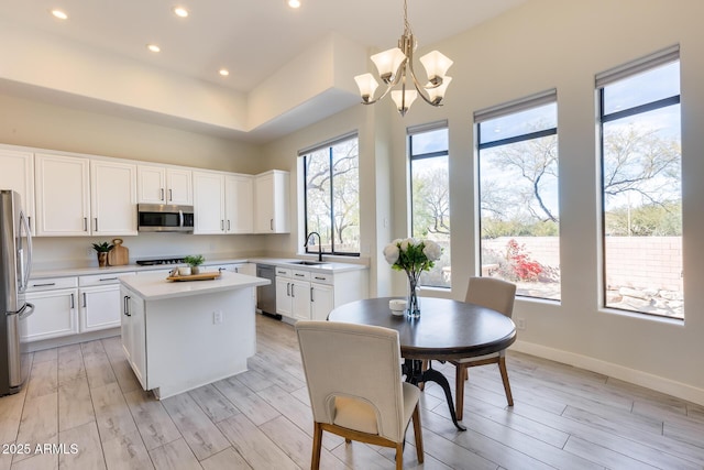 kitchen with a kitchen island, white cabinetry, appliances with stainless steel finishes, and hanging light fixtures