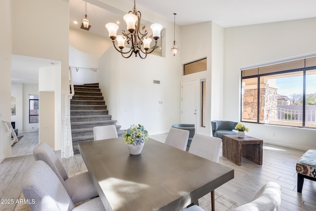 dining space featuring a chandelier, high vaulted ceiling, and light hardwood / wood-style floors