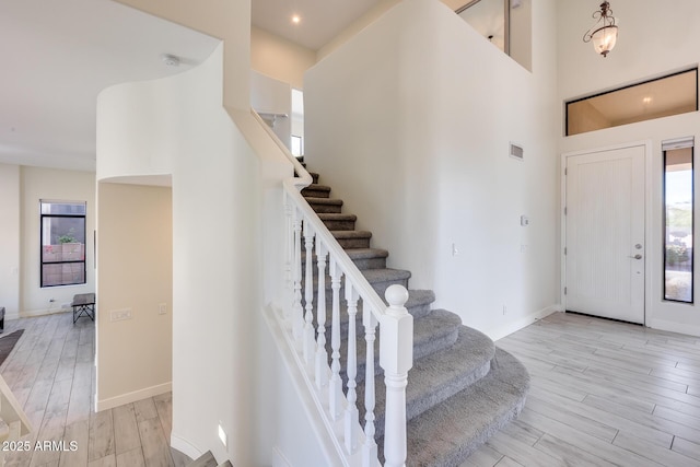 entrance foyer featuring a towering ceiling and light hardwood / wood-style floors