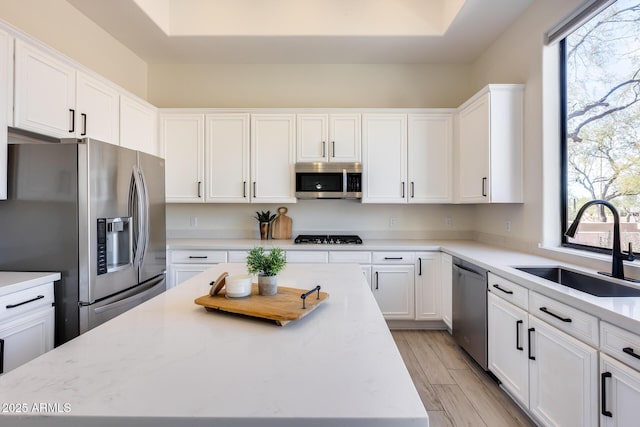 kitchen featuring stainless steel appliances, a center island, sink, and white cabinets