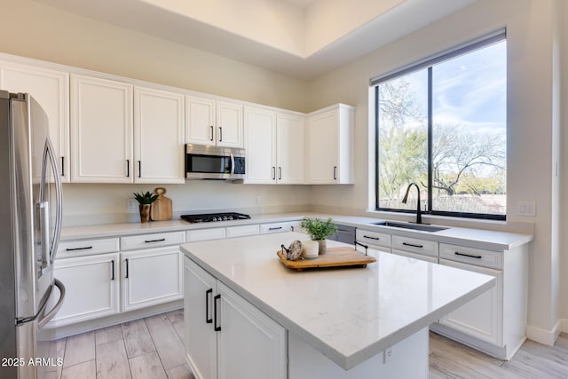 kitchen featuring stainless steel appliances, a center island, sink, and white cabinets