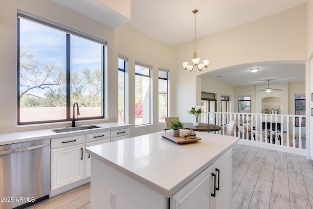 kitchen featuring dishwasher, sink, white cabinets, hanging light fixtures, and a center island