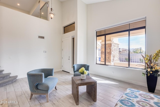 sitting room with light hardwood / wood-style floors and a high ceiling