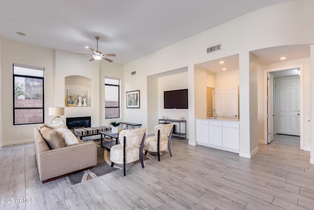 living room with sink, light hardwood / wood-style floors, and ceiling fan