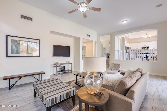 living room featuring ceiling fan with notable chandelier and light hardwood / wood-style floors