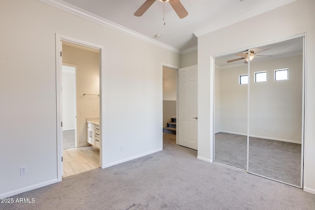 unfurnished bedroom featuring crown molding, light colored carpet, ceiling fan, and a closet