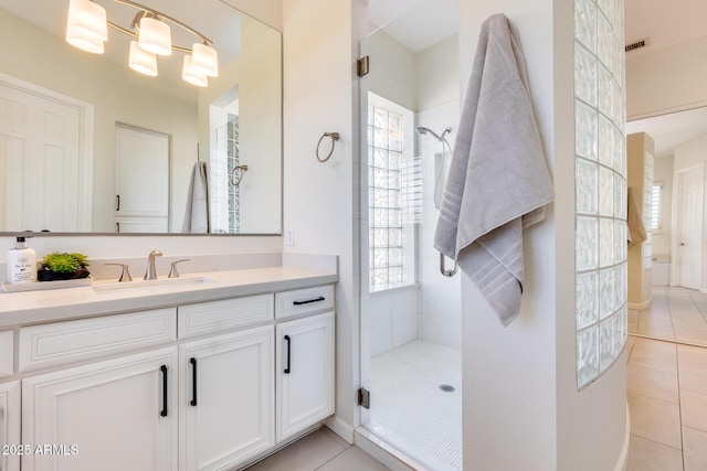 bathroom with a shower with door, vanity, and tile patterned floors