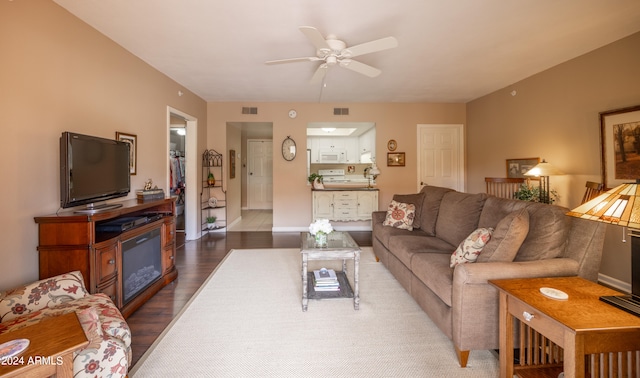 living room with dark wood-type flooring and ceiling fan