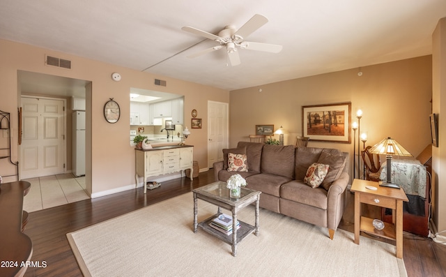 living room with light wood-type flooring, ceiling fan, and sink