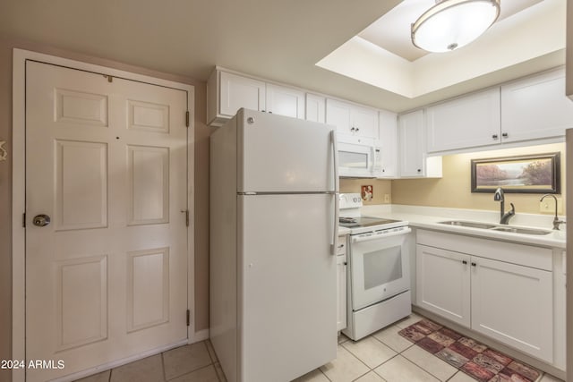 kitchen featuring white appliances, sink, light tile patterned floors, and white cabinets