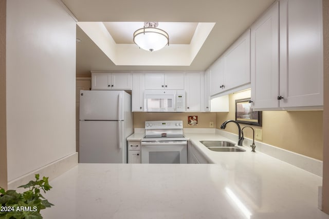 kitchen featuring white appliances, sink, a raised ceiling, and white cabinets