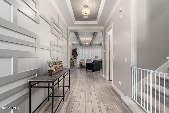 hallway with a tray ceiling, light wood-style floors, a notable chandelier, and baseboards