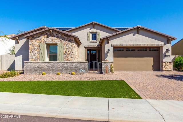 view of front of home featuring an attached garage, stucco siding, stone siding, and decorative driveway