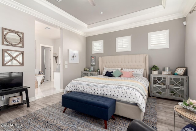 bedroom with multiple windows, wood finished floors, crown molding, and a raised ceiling