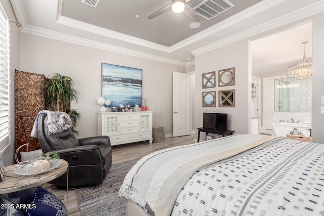 bedroom featuring a tray ceiling, wood finished floors, ornamental molding, and visible vents