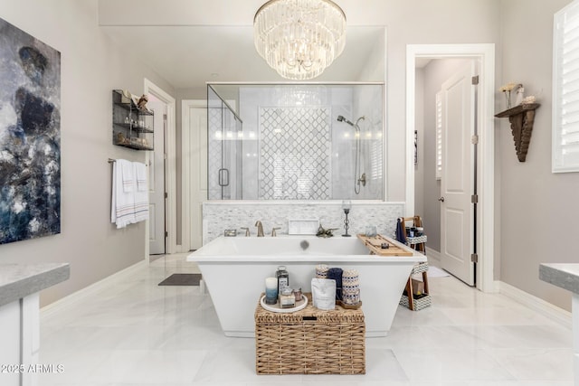 bathroom featuring baseboards, an inviting chandelier, a stall shower, a soaking tub, and marble finish floor