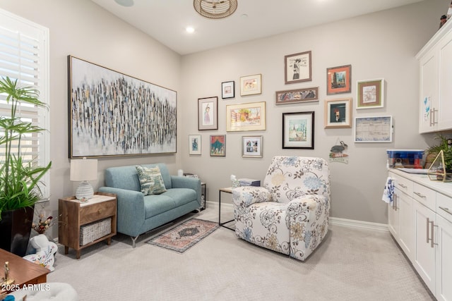 sitting room with baseboards, recessed lighting, and light carpet