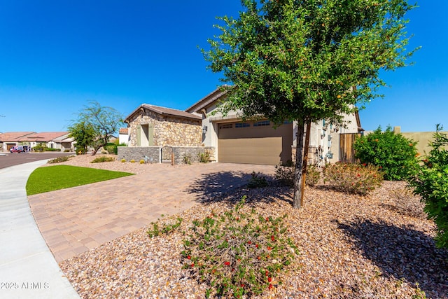 obstructed view of property featuring a garage, driveway, stone siding, and stucco siding