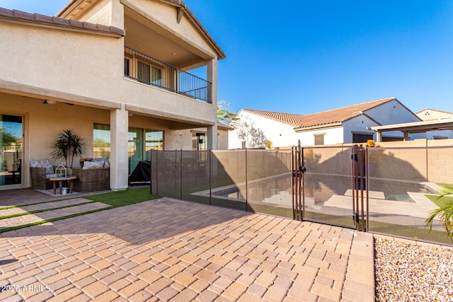 view of patio with fence, a balcony, and a gate