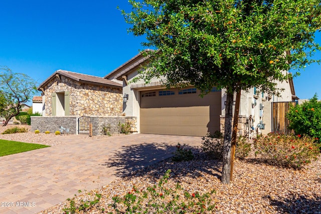 view of front of home featuring an attached garage, stone siding, fence, stucco siding, and driveway