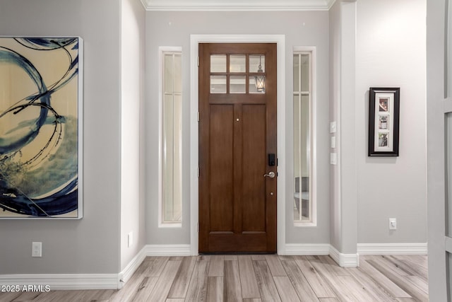 entryway with crown molding, light wood-style flooring, and baseboards