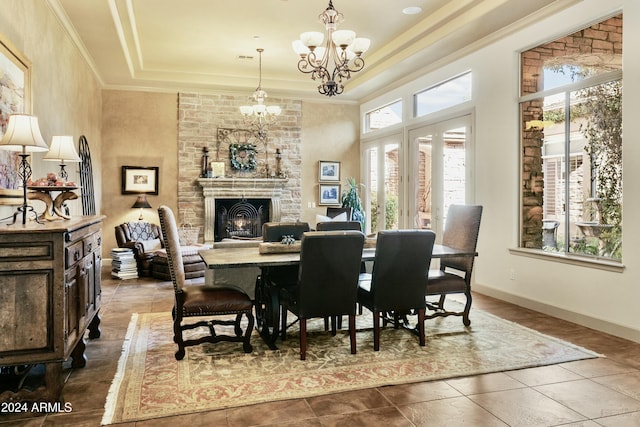 tiled dining space with a fireplace, a tray ceiling, an inviting chandelier, and crown molding