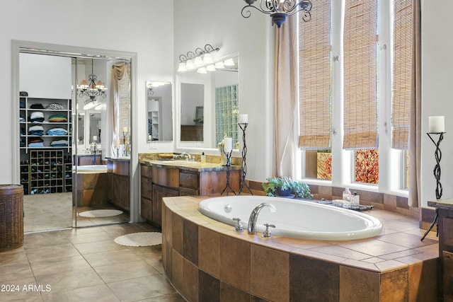 bathroom featuring a chandelier, vanity, a relaxing tiled tub, and tile patterned floors