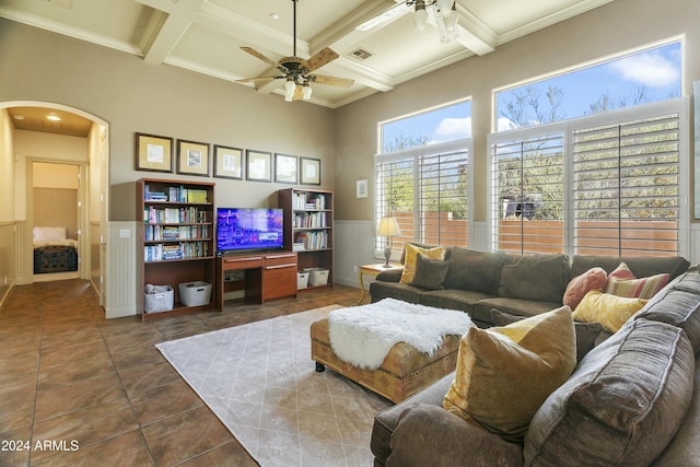 living room with ceiling fan, coffered ceiling, beamed ceiling, dark tile patterned flooring, and ornamental molding