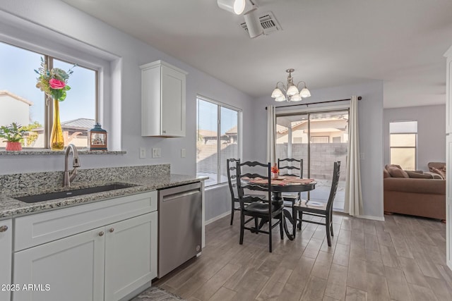 kitchen with sink, dishwasher, white cabinetry, light stone counters, and light hardwood / wood-style floors