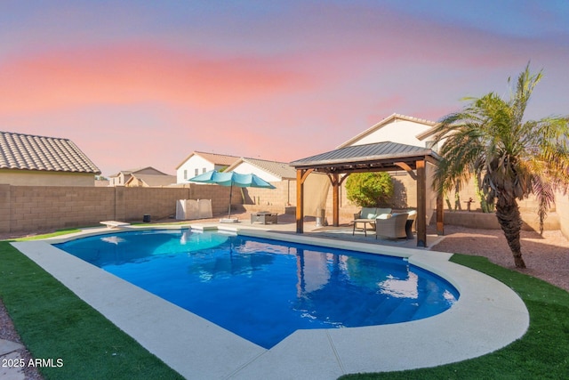 pool at dusk with a gazebo, an outdoor living space, a diving board, and a patio area