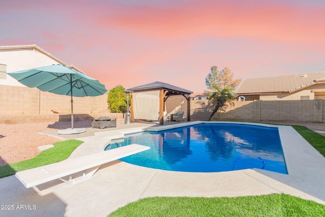 pool at dusk featuring a gazebo, a diving board, and a patio