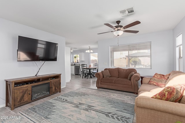 living room with ceiling fan with notable chandelier