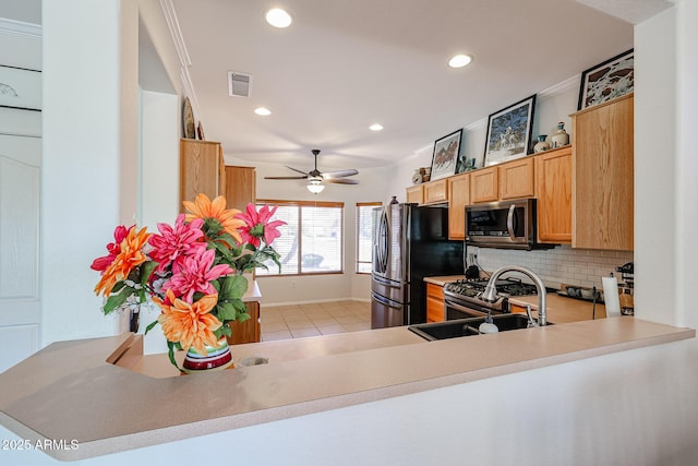 kitchen with tasteful backsplash, stainless steel microwave, visible vents, freestanding refrigerator, and a sink