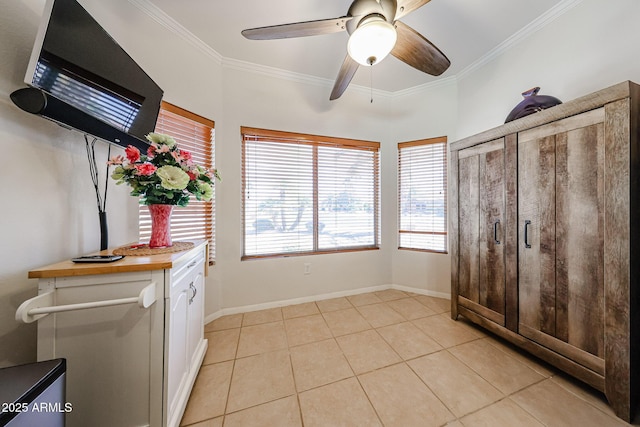 interior space with a healthy amount of sunlight, white cabinetry, ornamental molding, and light countertops